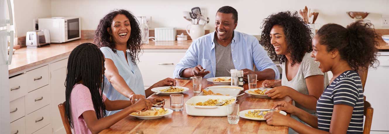 Family enjoys dinner and laughter around the kitchen table.