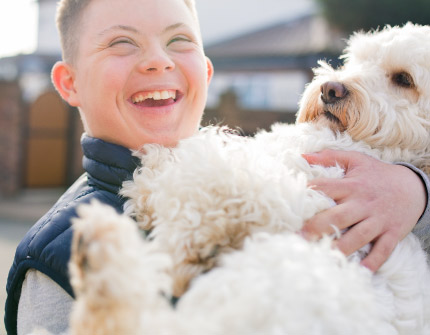 A young boy joyfully holds the family dog.