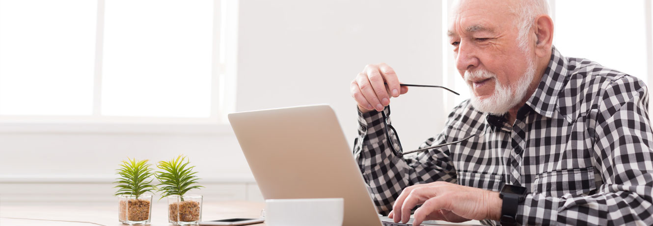 An older man checks his credit score on his laptop at home.
